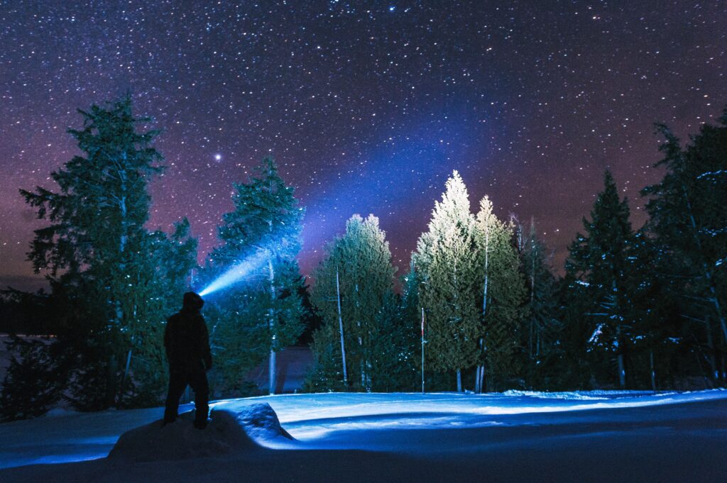 Man with headlight through forest at night is symbolic of exploring intuitive dreams and astrology.
